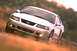 2003 Ford Mustang - A white 2003 Ford Mustang is captured in a dynamic shot, kicking up dust as it drives on a dirt road.