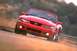 2003 Ford Mustang - Red 2003 Ford Mustang convertible captured in motion on a winding road.