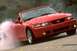 2003 Ford Mustang - A red 2003 Ford Mustang convertible is shown performing a burnout, with smoke billowing from the rear tire.