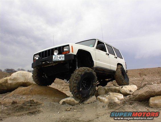 White Jeep Cherokee XJ climbing rocks, front 3/4 view