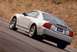 2003 Ford Mustang - A silver 2003 Ford SVT Mustang Cobra is captured in a rear 3/4 view, driving on a winding road.