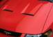 2003 Ford Mustang - Close-up of the hood on a red 2003 Ford Mustang, dual vents and the iconic running horse emblem.