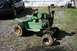 1987 Ford Bronco - A weathered green lawn tractor sits outside on a gravel driveway, with a black car parked nearby.