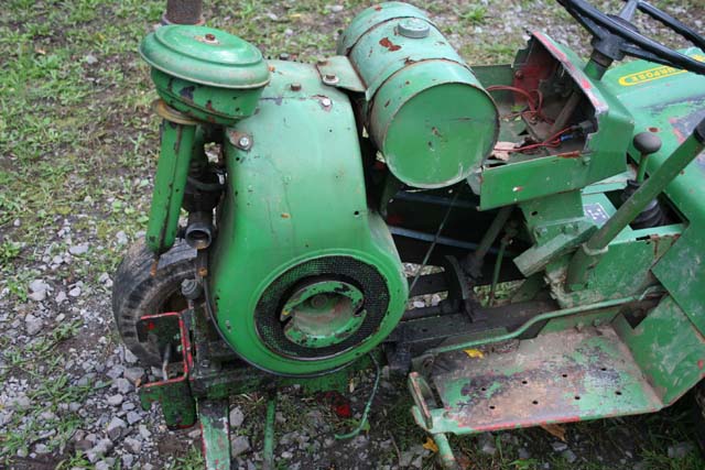 Green tractor engine with air filter and fuel tank, showing part of the chassis and steering wheel