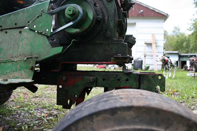 Close-up of green agricultural machinery with a dog in the background