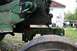 1987 Ford Bronco - A dog walks near some old green farm equipment in a grassy yard.
