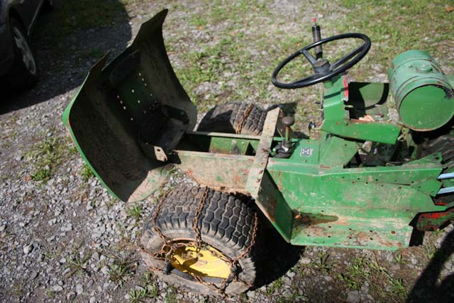 Green tractor with hood open, showing engine area and tire chains