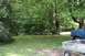 1987 Ford Bronco - A blue truck with a brown hood is partially visible on the right side of the frame, parked on a lawn.