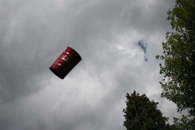 Red barrel suspended against a cloudy sky with trees on the right
