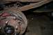 1987 Ford Bronco - Close-up view of a rusty rear drum brake assembly and leaf springs.