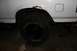 1987 Ford Bronco - The rear wheel well of a white vehicle shows significant rust around the fender opening.