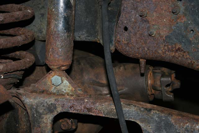 Close-up of heavily rusted vehicle suspension parts, including a shock absorber and coil spring