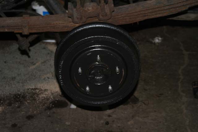 Black painted rear drum brake assembly with leaf spring and suspension components above