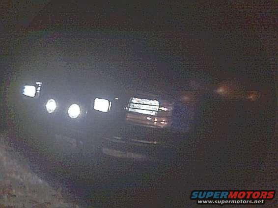 1994 Ford Bronco front with headlights and fog lights on at night