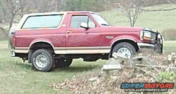 Red Ford Bronco with a tan top parked on grass