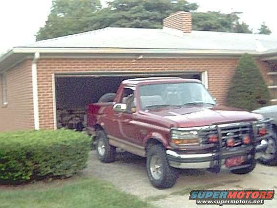 Red Ford F-Series pickup truck, likely 1992-1996, parked in front of a garage