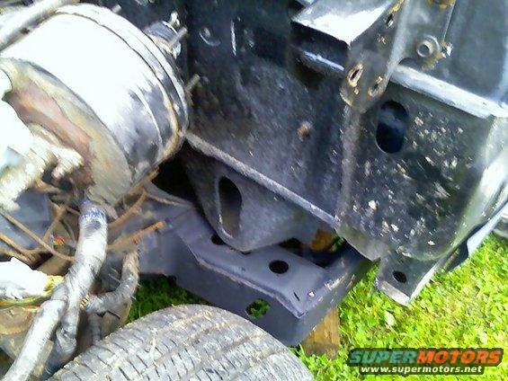 Close-up of a vehicle's brake booster and part of the frame, with a tire visible in the foreground