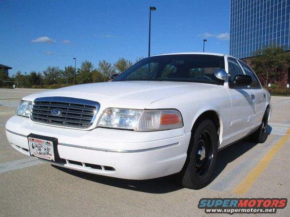 White sedan parked in a lot, front quarter view. Has black steel wheels and a chrome grille
