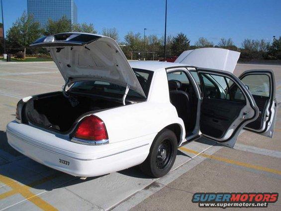 White 1998 Ford Crown Victoria with trunk and all four doors open, parked in a lot