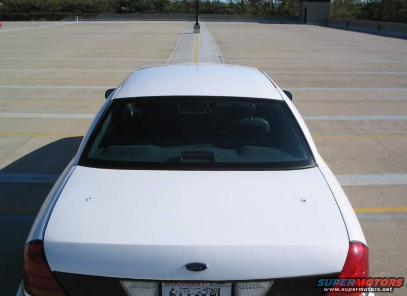 Rear view of a white sedan parked in a lot. License plate is visible