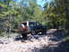 1988 Ford Bronco - This SUV, likely a 1987-1991 Ford Bronco, navigates a challenging rocky path through a wooded area.