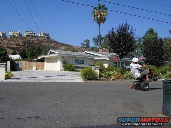 Person on three-wheeled vehicle doing a wheelie, side view. Text 'SUPERMOTORS' visible