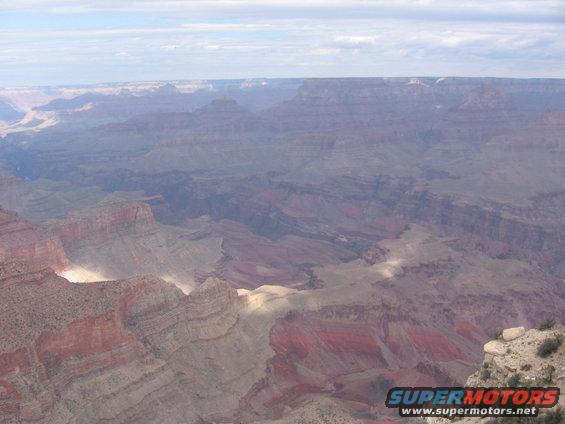 Wide view of Grand Canyon with layered rock formations and a cloudy sky