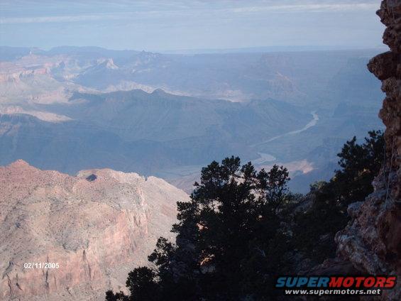 Grand Canyon vista with river in distance, trees in foreground, rock formations on right. Date stamp 02/11/2005