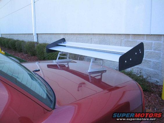 Red car with a large silver spoiler mounted on the trunk