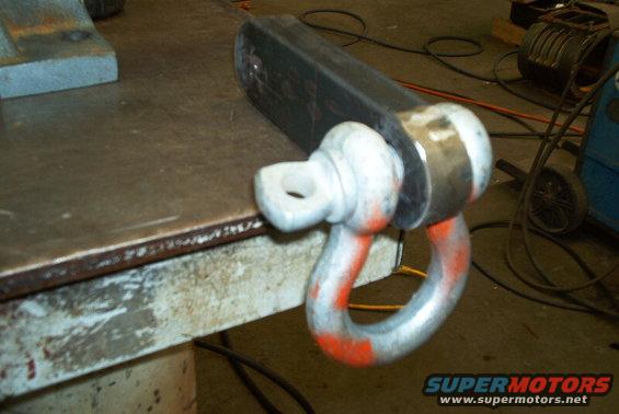 Metal shackle attached to a heavy-duty tow hitch receiver, resting on a workbench