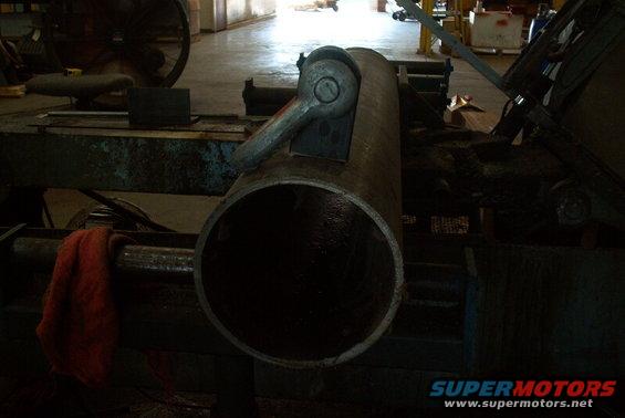 Metal pipe with clamp mechanism on industrial machinery, red cloth nearby