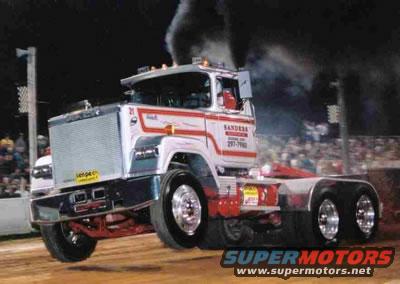 Custom semi-truck with "SANDERS" and phone number on the door, emitting black smoke during a pull event