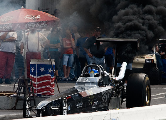 Dragster with black smoke billowing from behind, front view
