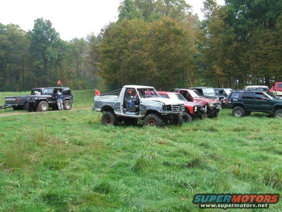 1995 Ford Bronco with front end damage parked in a line with other off-road vehicles