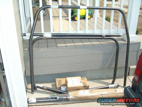 Roll cage parts on deck with boxes and a toy tractor in background