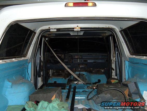 1993 Ford Bronco interior with roll cage installed, seats removed, and bed liner visible