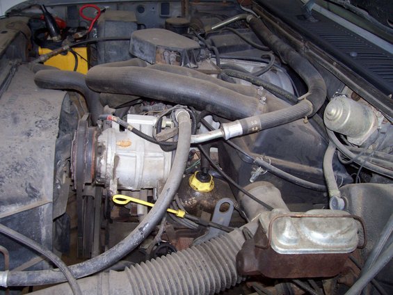 Engine bay with air conditioning compressor, fan, and brake fluid reservoir visible