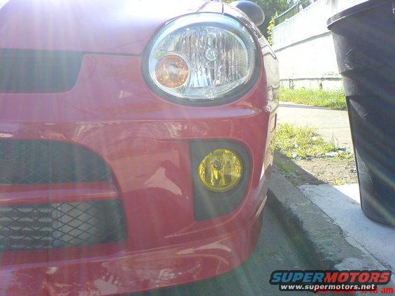 Front view of red Dodge Neon with yellow fog lights and mesh grille