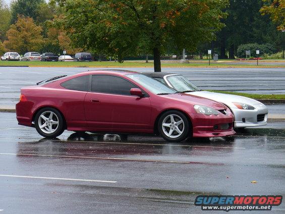 Red coupe parked next to silver convertible on wet pavement