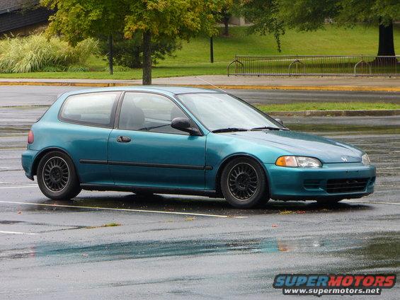 Teal 1990s Honda Civic hatchback parked on wet asphalt