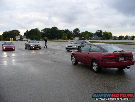 Red 1991 Ford Probe coupe from rear, license plate V404, on wet asphalt
