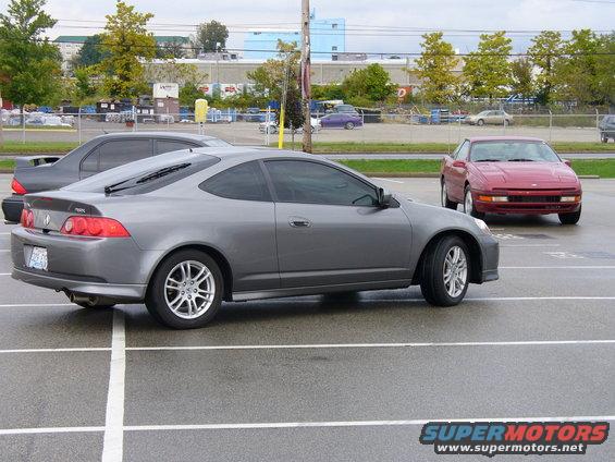 Gray Acura RSX parked in a lot, red car behind it
