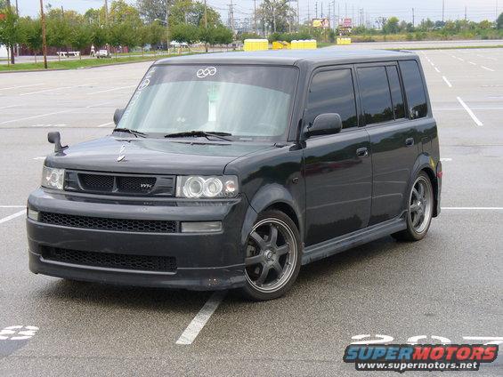 Black Scion xB parked in a lot, front quarter view. Has a sticker on the windshield