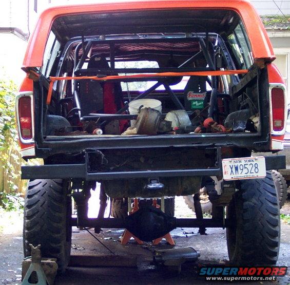 Orange 1978 Ford Bronco rear view, modified with roll cage, large tires, and lifted suspension. Rear differential is exposed
