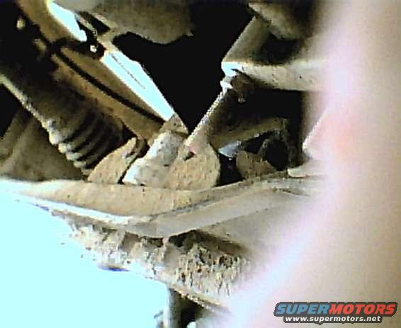 Close-up of rusted metal components, possibly from a vehicle undercarriage. Supermotors.net logo visible
