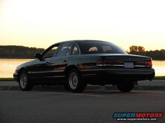 Black Ford Crown Victoria parked by a lake at sunset