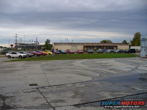 Several cars parked in a line on grass in front of a building