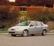 2002 Ford Focus - This silver 2002 Ford Focus sedan is seen from a three-quarter front view, parked on pavement with a brick building in the background.