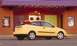 2002 Ford Focus - A yellow 2002 Ford Focus hatchback is parked on the street in front of a building with colorful doors and posters.