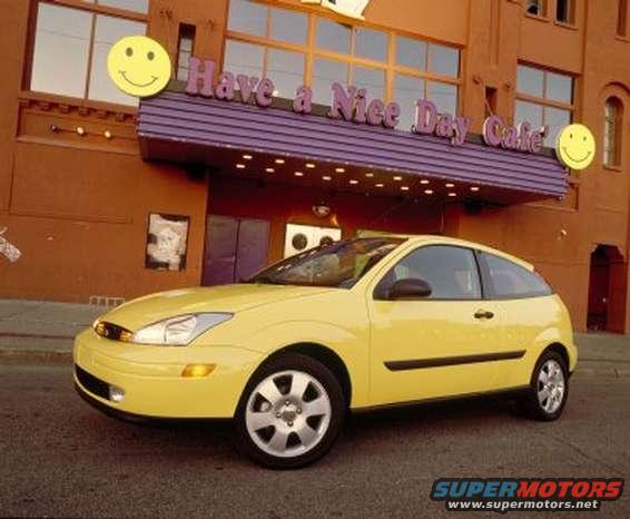 Yellow 2002 Ford Focus parked outside a cafe with a purple awning and smiley face signs